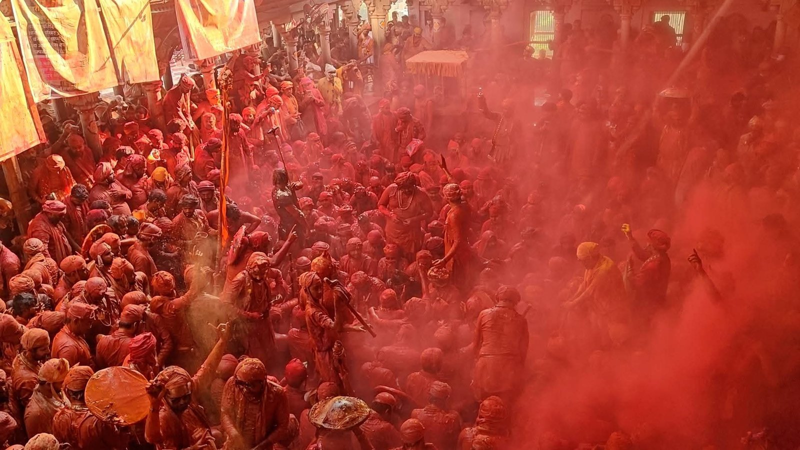 Devkinandan Maharaj spraying colors with hydraulic pichkari at Brindavan Holi festival; 1000 widows and foreign women celebrating with flowers and gulal.