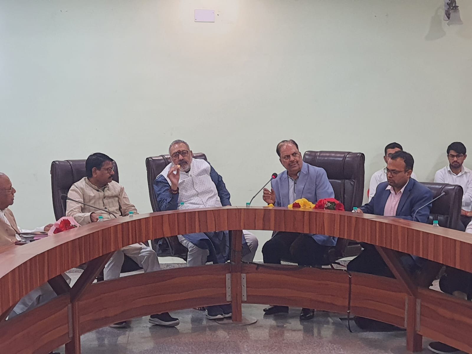 Minister conducting an official meeting with government officials and stakeholders during a review discussion