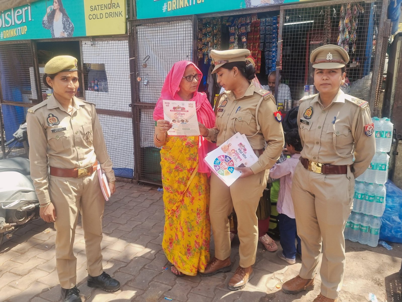 “Women being educated under Mission Shakti campaign in Fatehabad about safety, rights, and emergency helpline numbers by officials distributing pamphlets”