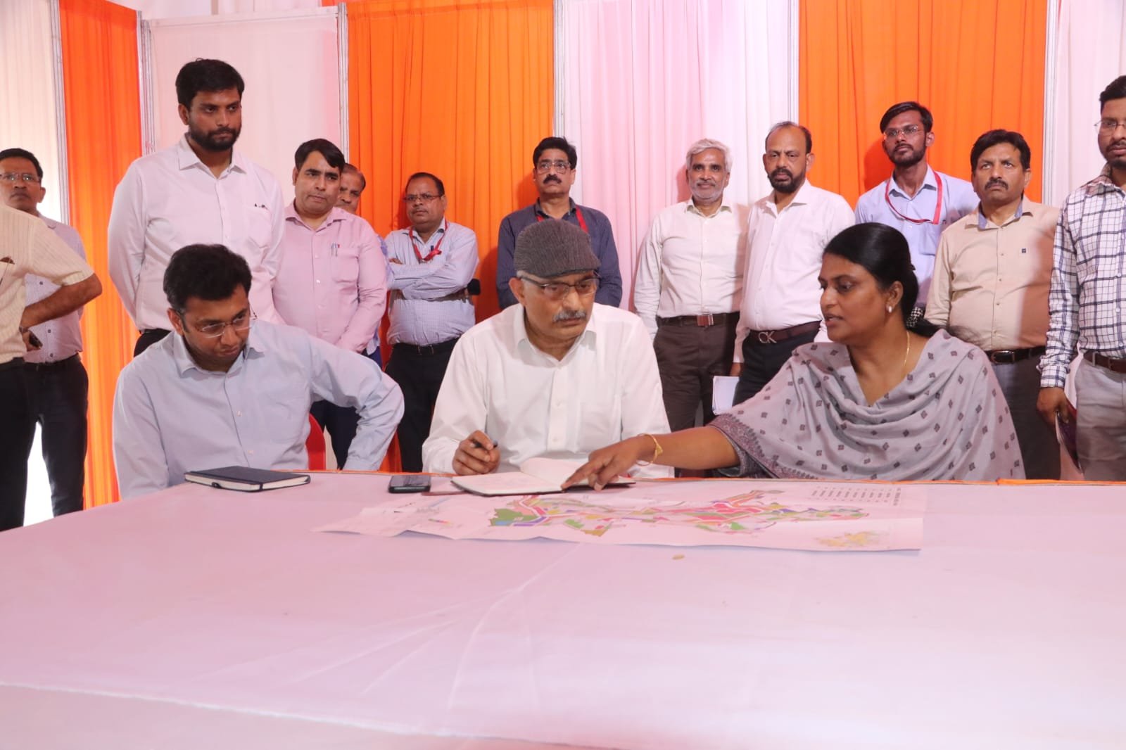 Officials inspecting preparations for Chief Minister Yogi Adityanath visit in Agra, reviewing township project site, helipad, barricading, and public meeting arrangements.