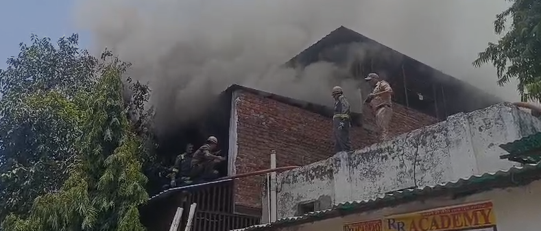 Firefighters extinguishing a massive fire at a two-storey shoe factory in Jagdishpura, Agra, as thick black smoke and flames engulf the building.