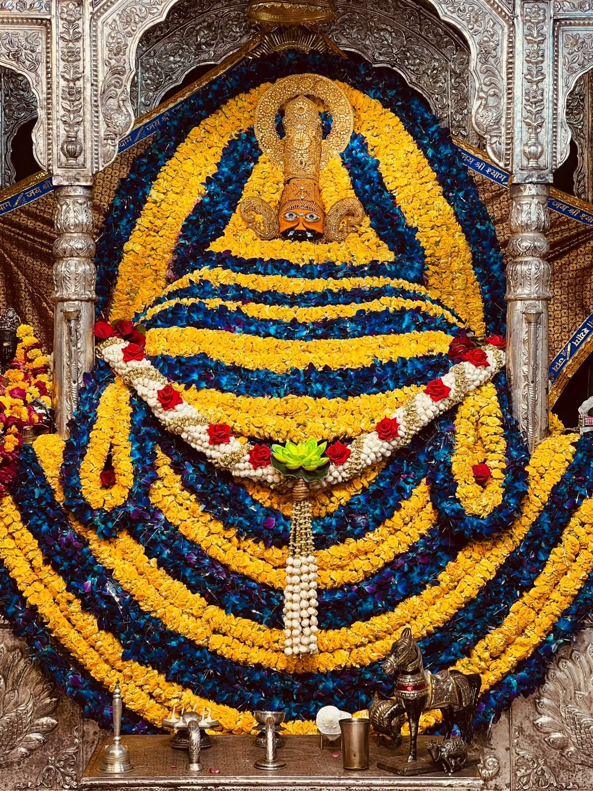 Shyam Baba adorned with blue and yellow flowers, golden crown, ornaments and dry fruit garland on Parivartini Ekadashi